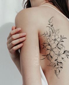 a woman with a flower tattoo on her back and shoulder, holding onto the arm