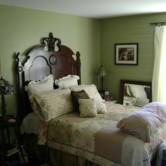 a bedroom with green walls and white bedspread on the bed is decorated in an antique style