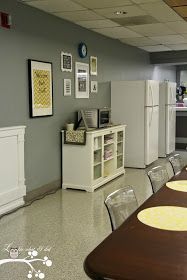 a kitchen with white appliances and pictures on the wall, along with glass dining chairs