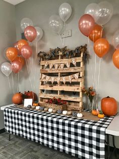 a table topped with lots of balloons next to a wooden crate filled with pumpkins