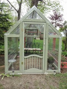 a small green house sitting in the middle of a yard