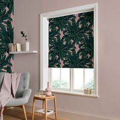 a living room with a window covered in green leafy blinds and a chair next to the window