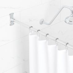 a white shower curtain hanging on the side of a bathtub with handles and bars