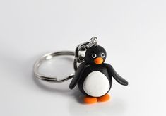 a penguin keychain with an orange nose and black beak, sitting on a white surface