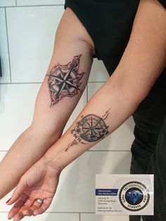 two people holding hands with tattoos on their arms and one has a compass tattoo on the arm