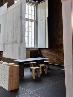 an empty room with tables and stools in front of a large white sheet on the wall