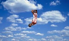 two people standing on the beach flying a kite in the blue sky with white clouds