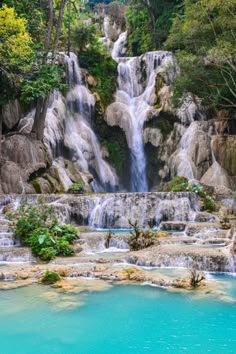 the waterfall is surrounded by trees and blue water