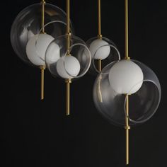 several glass balls hanging from gold poles on a black background