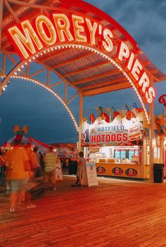 people are walking under the marquee at an amusement park with lights on it