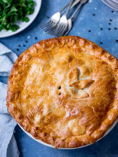 a pie sitting on top of a white plate next to a fork and silverware