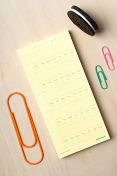 a notepad, pen, and cookie on a table next to some office supplies