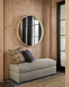 a couch with pillows and a round mirror on the wall