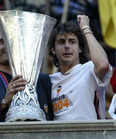 a man holding up a silver trophy in front of him and another person behind him