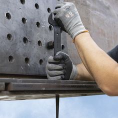 a man working on a piece of metal with a pair of wrenches in his hand