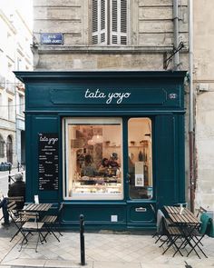 a store front with tables and chairs outside on the sidewalk in an old city street