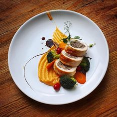 a white plate topped with slices of bread and veggies on top of a wooden table