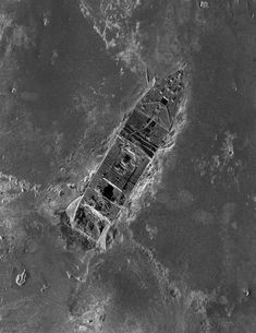 an aerial view of a ship in the middle of the ocean with rocks and water around it