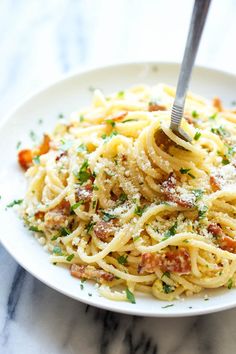 a white plate topped with pasta covered in sauce and parmesan cheese