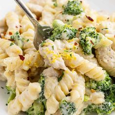 a white plate topped with pasta and chicken covered in broccoli florets