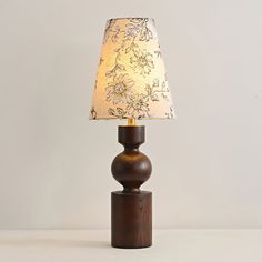 a wooden table lamp with a fabric shade on it's base and a floral print lampshade