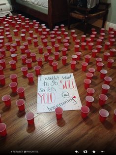 a bunch of red cups sitting on top of a wooden floor next to a sign