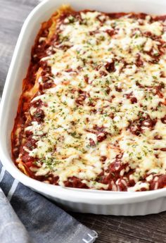 a casserole dish with meat, cheese and sauce in it on a wooden table