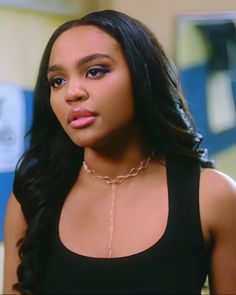 a close up of a person wearing a black shirt and necklace with a chain around her neck