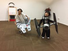 two children dressed up as darth vader and r2d2, standing on the floor