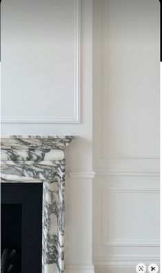 a white fireplace with black and white marble surround