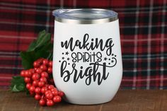 a white wine glass with the words making spirits bright on it next to some red berries