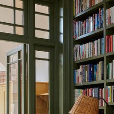 a bookshelf filled with lots of books next to a window in a room