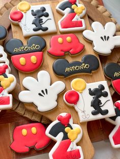 mickey mouse cookies are arranged on a wooden platter with the names of each character