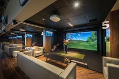 a man is playing golf on the large screen in this modern home theater room with white couches and wooden flooring