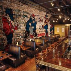 the interior of a restaurant with graffiti painted on the brick wall and wooden tables in front of it