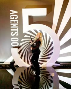 a woman standing in front of a sign with the number five on it's side