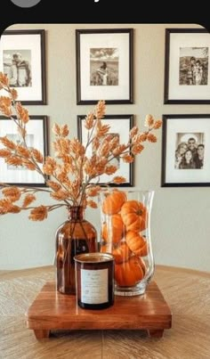 an arrangement of pumpkins in a vase on a table with pictures above it and below