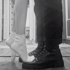 a man and woman standing next to each other on a hard wood floor in black and white