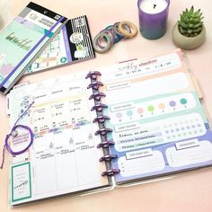 an open planner sitting on top of a table next to a candle