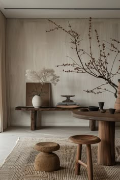 a table with two stools and a vase on top of it in front of a wall