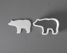 two white plastic polar bears standing next to each other on a gray surface with one bear facing the other way