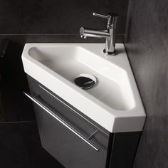 a white sink sitting under a faucet on top of a counter next to a black wall