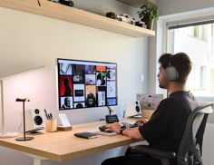 a man wearing headphones sitting at a desk in front of a computer monitor and keyboard