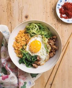 korean bibimbap with meat and vegetables in a white bowl on a wooden table