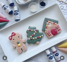 some decorated cookies on a white tray with markers and crayons next to it