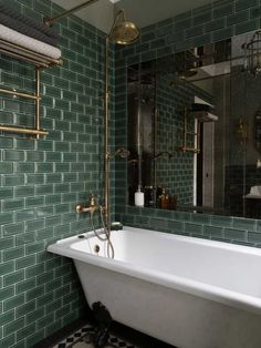 the bathroom is decorated in green and white tiles with gold fixtures, including a claw foot bathtub