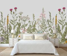 a white bed sitting in front of a wall with lots of wildflowers on it