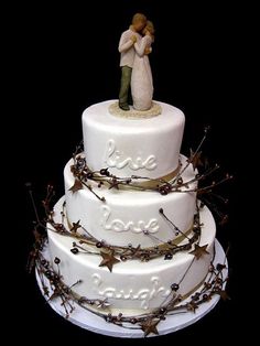 a wedding cake with a bride and groom figurine on top, surrounded by branches