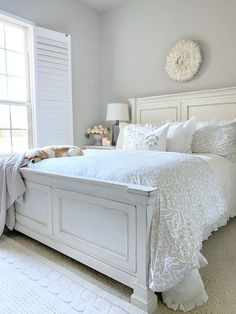 a white bed sitting in a bedroom next to a window