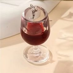 a wine glass filled with red liquid on top of a white tablecloth covered table